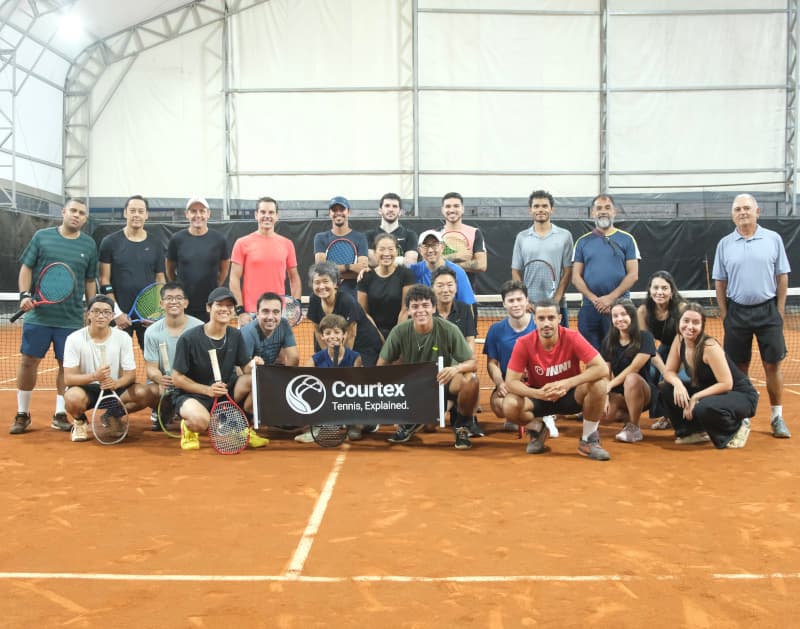 Clínica presencial de tênis avançado com alunos aprendendo biomecânica e tática